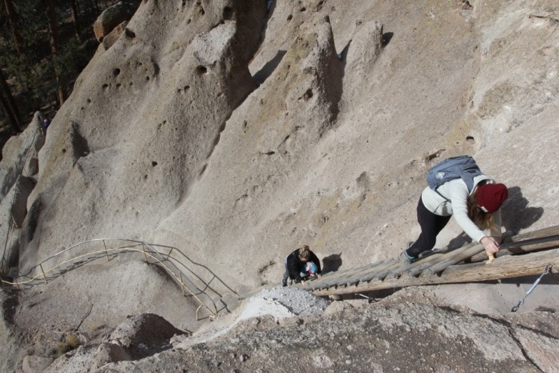 A mother takes her child on the steep ladders to the alcove house
